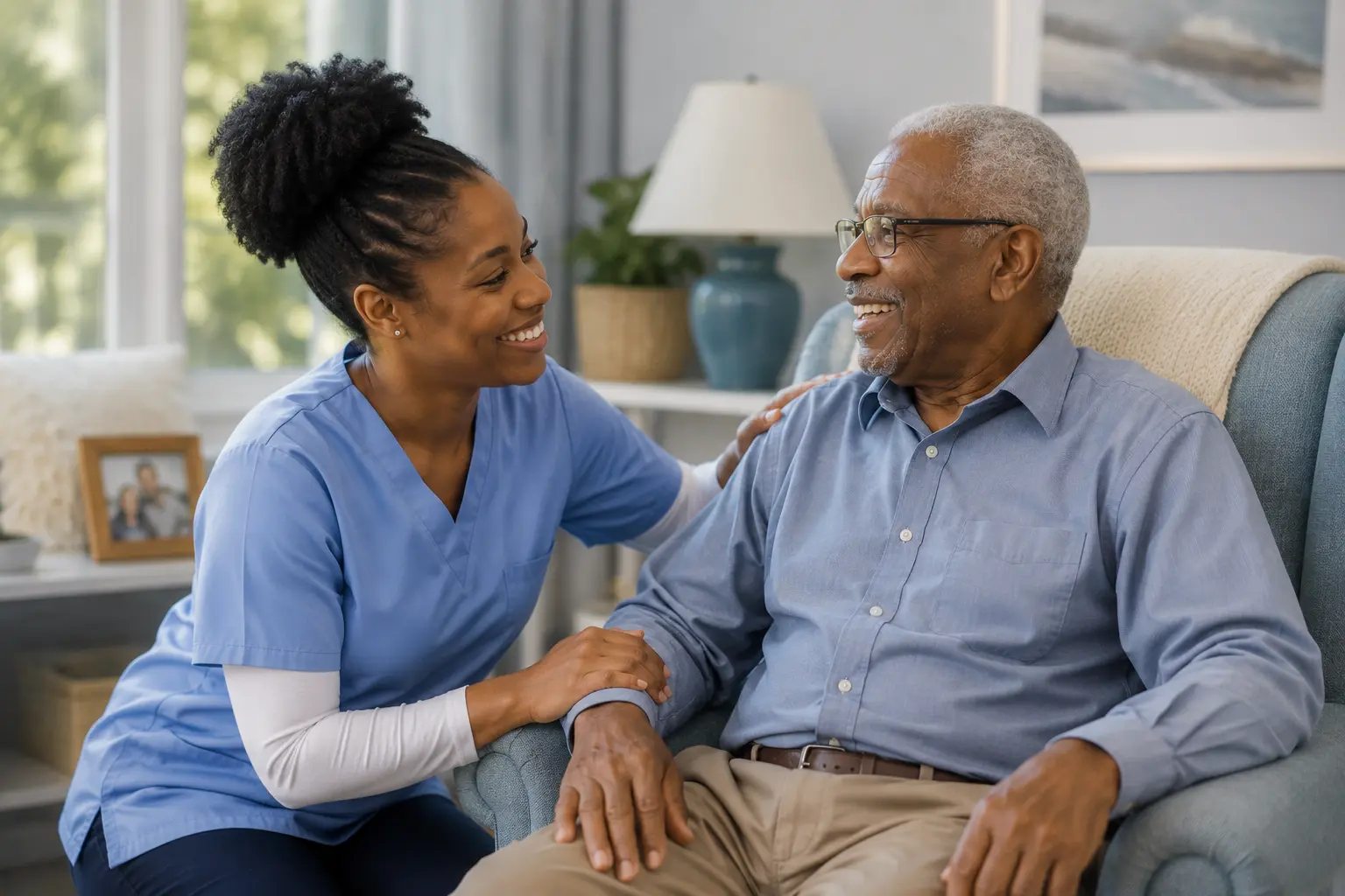 A companion kneeling beside an elderly man in his armchair, smiling as they talk